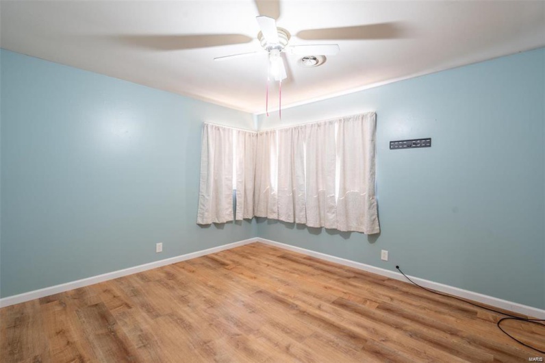 Unfurnished room with baseboards, wood finished floors, and a ceiling fan