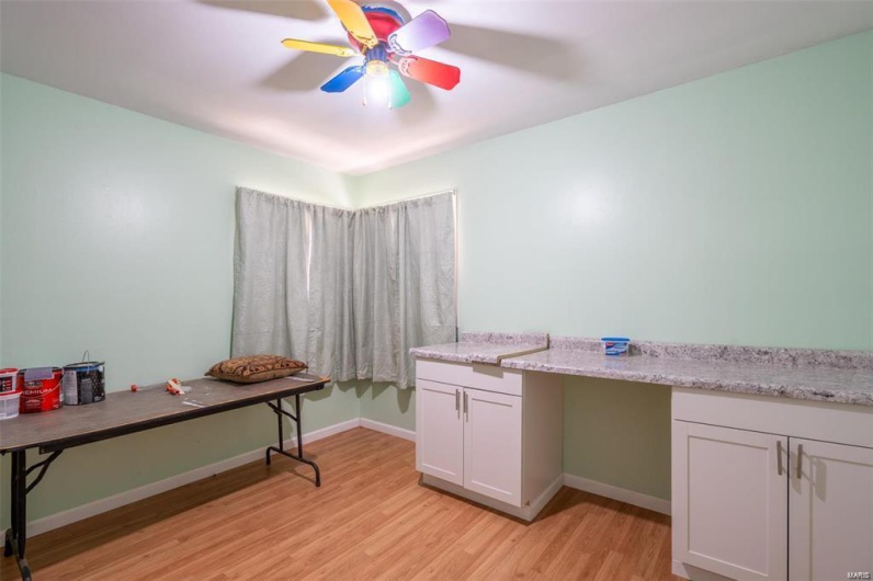 Home office with light wood-style flooring, baseboards, and ceiling fan
