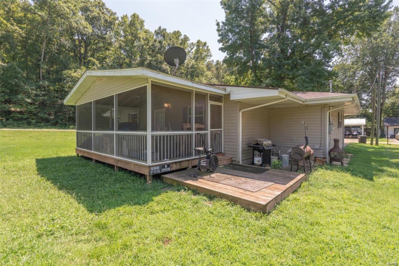 Rear view of property featuring a lawn and a sunroom