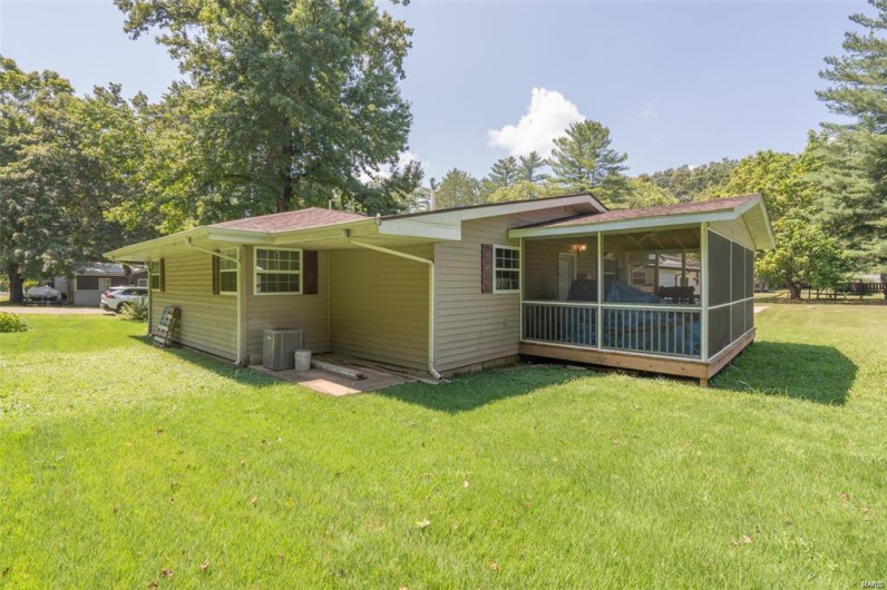 Back of property featuring central air condition unit, a lawn, and a sunroom