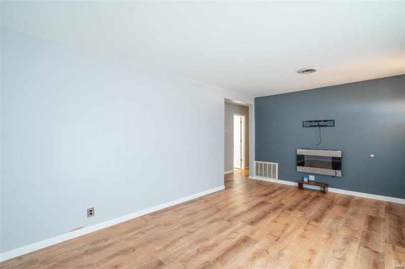 Unfurnished living room featuring visible vents, wood finished floors, and baseboards