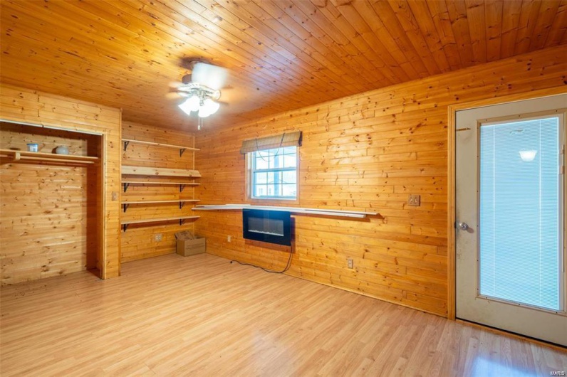 Kitchen with a ceiling fan, wooden ceiling, wooden walls, and light wood-style floors