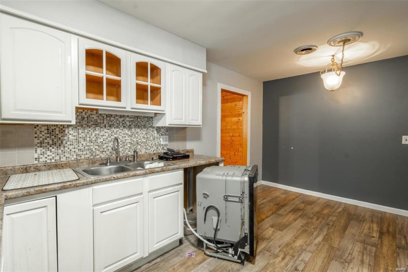 Kitchen featuring a sink, glass insert cabinets, tasteful backsplash, and white cabinetry