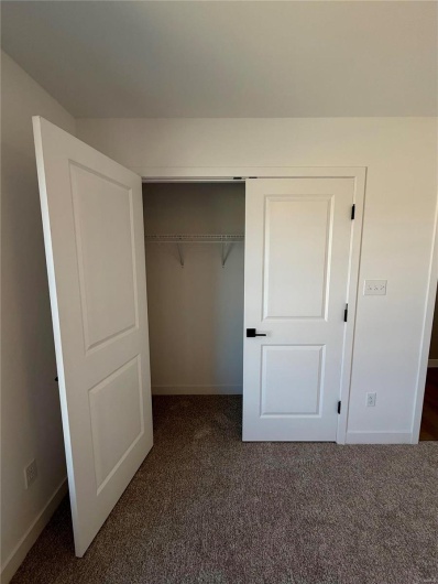 Unfurnished bedroom with baseboards, dark colored carpet, and a closet