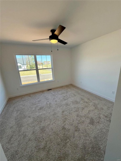 Carpeted empty room with visible vents, baseboards, and ceiling fan