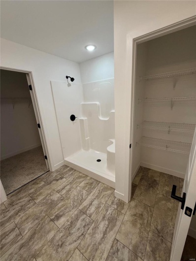 Full bathroom with a shower stall, a walk in closet, and baseboards