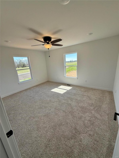 Carpeted spare room featuring ceiling fan and baseboards