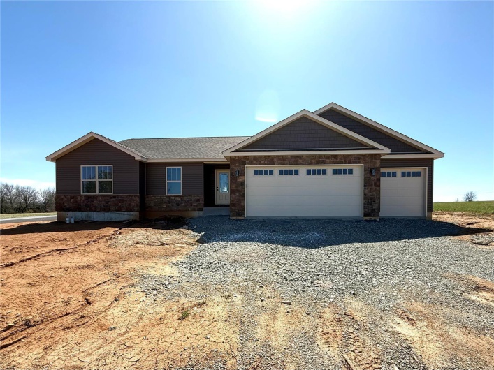 View of front of property featuring gravel driveway, an attached garage, and roof with shingles