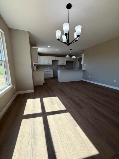 Kitchen with a notable chandelier, white cabinets, dark wood-type flooring, and baseboards