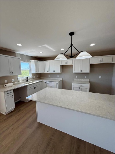 Kitchen featuring a sink, light stone counters, dark wood finished floors, recessed lighting, and white cabinets