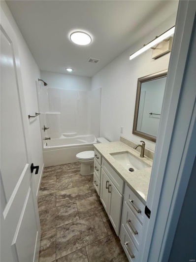 Bathroom featuring vanity, toilet, washtub / shower combination, and visible vents