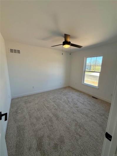 Carpeted spare room with visible vents, baseboards, and ceiling fan