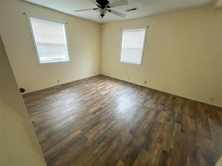 Empty room with ceiling fan, dark wood-type flooring, and a textured ceiling