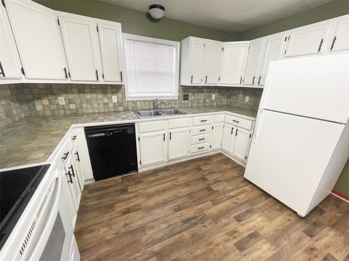 Kitchen featuring white cabinets, white fridge, sink, and black dishwasher