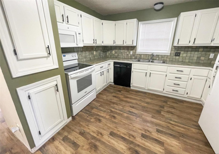 Kitchen featuring white cabinetry, sink, dark wood-type flooring, a textured ceiling, and white appliances