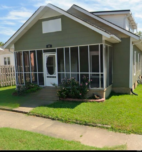 View of front of house featuring a sunroom, a front lawn, and fence