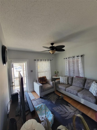 Living area featuring ceiling fan, a textured ceiling, and wood finished floors