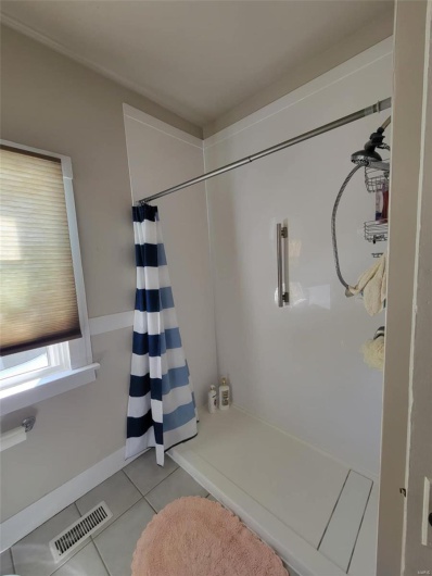 Bathroom featuring tile patterned flooring, visible vents, and curtained shower