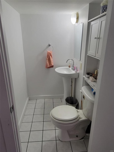 Half bathroom featuring tile patterned floors, toilet, baseboards, and a sink
