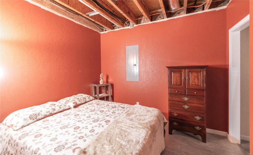Bedroom with electric panel and baseboards