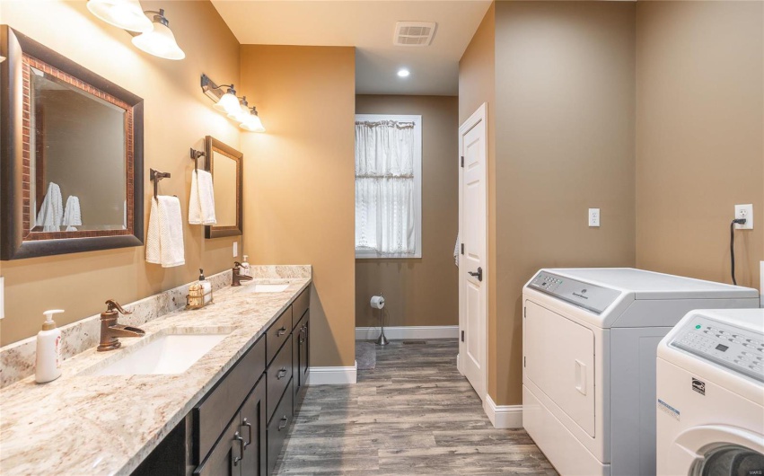 Bathroom with visible vents, baseboards, wood finished floors, washer and dryer, and a sink