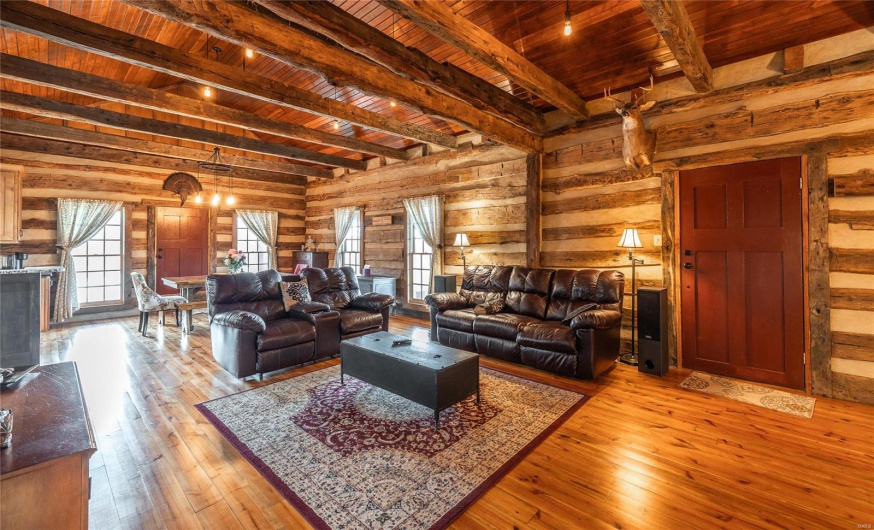 Living room featuring beamed ceiling, wood ceiling, light wood-style flooring, and wood walls