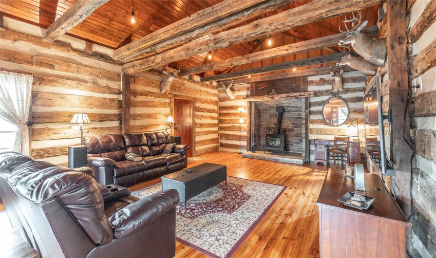 Living area featuring wooden ceiling, vaulted ceiling with beams, a wood stove, and wood-type flooring