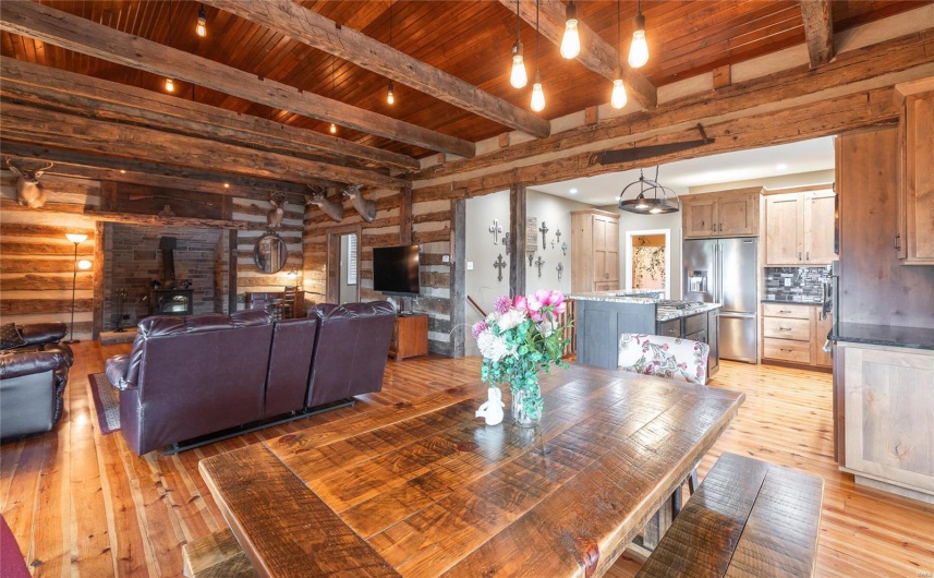 Dining area featuring beam ceiling, a wood stove, wood ceiling, and light wood-type flooring