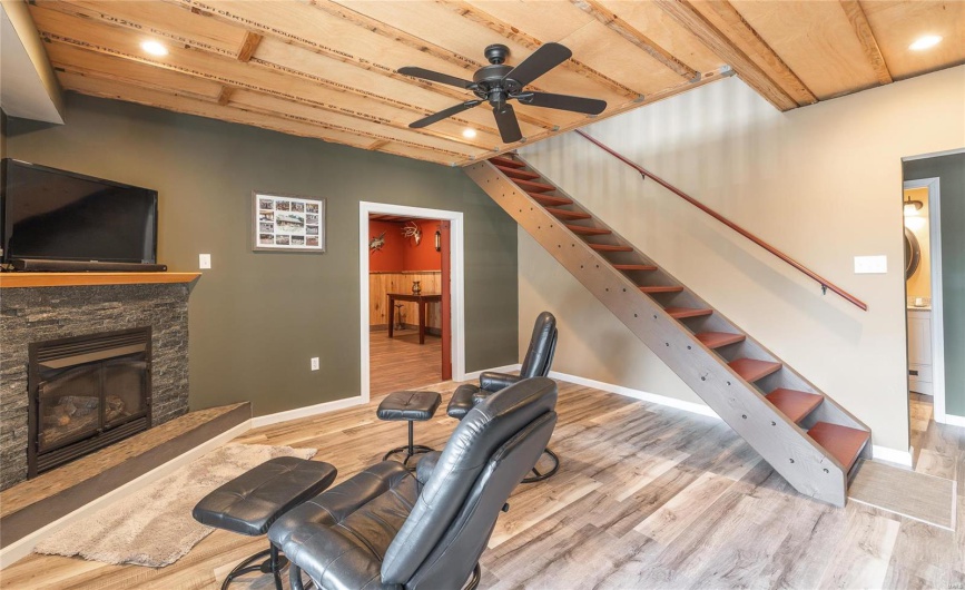 Living area featuring ceiling fan, baseboards, wood finished floors, and stairs