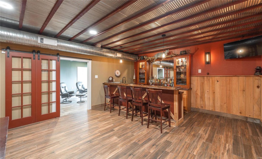 Bar with visible vents, baseboards, a barn door, wet bar, and wood finished floors