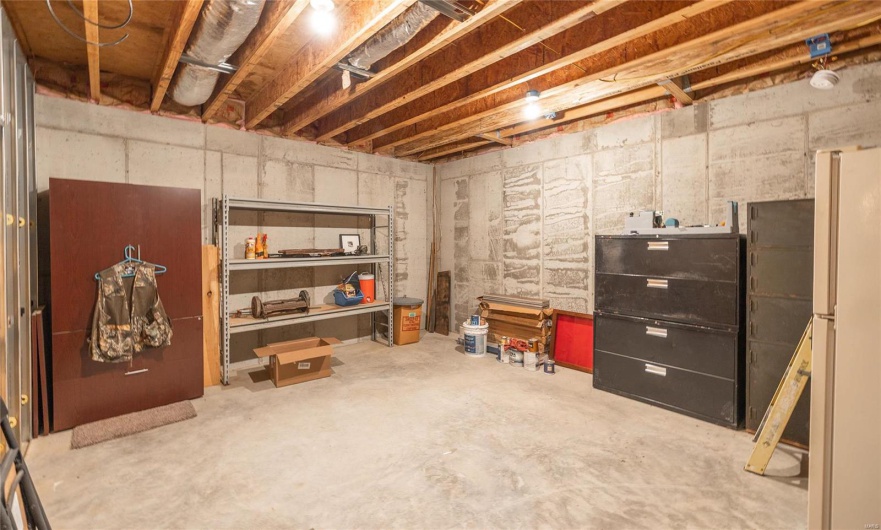 Unfinished below grade area featuring freestanding refrigerator