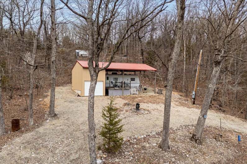 View of outbuilding featuring a forest view, a porch, and driveway