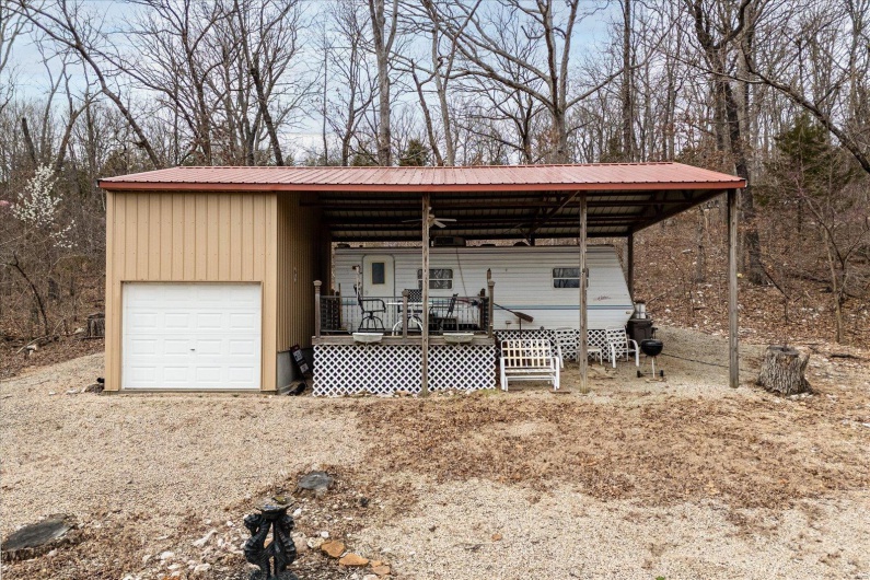 View of outbuilding featuring a carport, a porch, and a garage