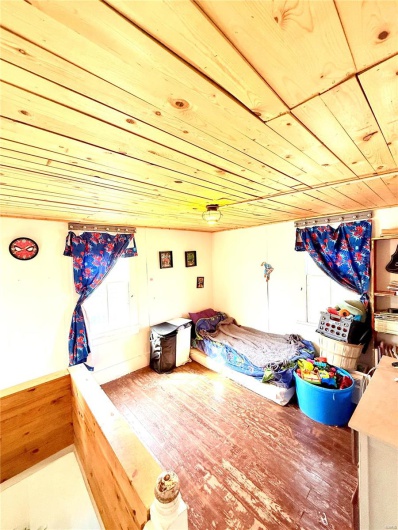 Unfurnished bedroom with a wainscoted wall, wood finished floors, and wooden ceiling