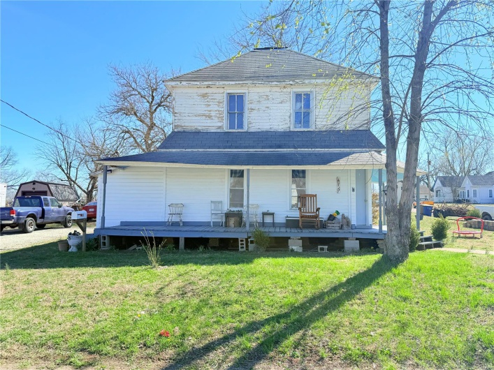 View of front of home featuring a front yard, covered porch, and roof with shingles