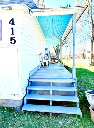 Wooden terrace featuring a lawn and a porch