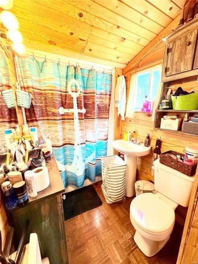Bathroom with vaulted ceiling, toilet, wood ceiling, wooden walls, and curtained shower