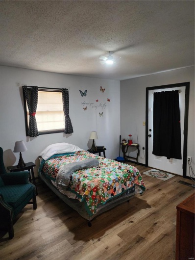 Bedroom featuring wood-type flooring, ceiling fan, and a textured ceiling