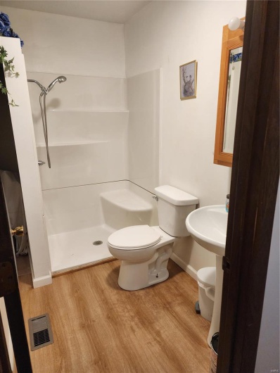 Bathroom with hardwood / wood-style floors, toilet, and a shower