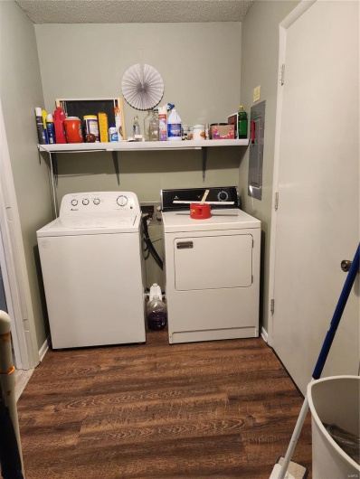 Laundry area featuring separate washer and dryer, dark wood-type flooring, electric panel, and a textured ceiling