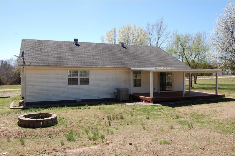 Back of house featuring central AC unit, a lawn, a shingled roof, and an outdoor fire pit