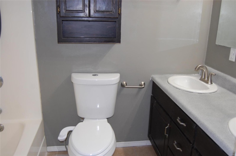 Bathroom featuring tile patterned flooring, toilet, baseboards, a sink, and double vanity