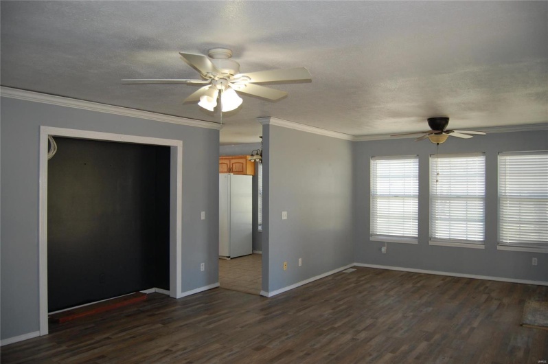 Unfurnished room featuring dark wood finished floors, baseboards, crown molding, and a ceiling fan