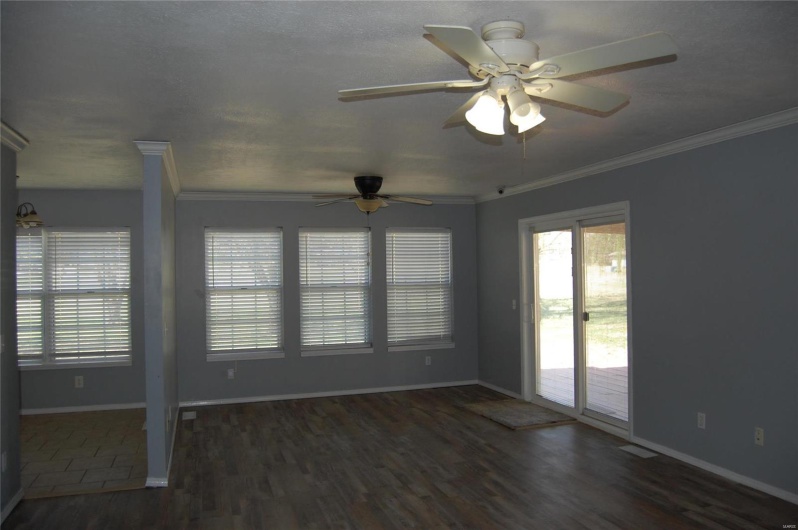 Empty room with baseboards, wood finished floors, ceiling fan, and ornamental molding
