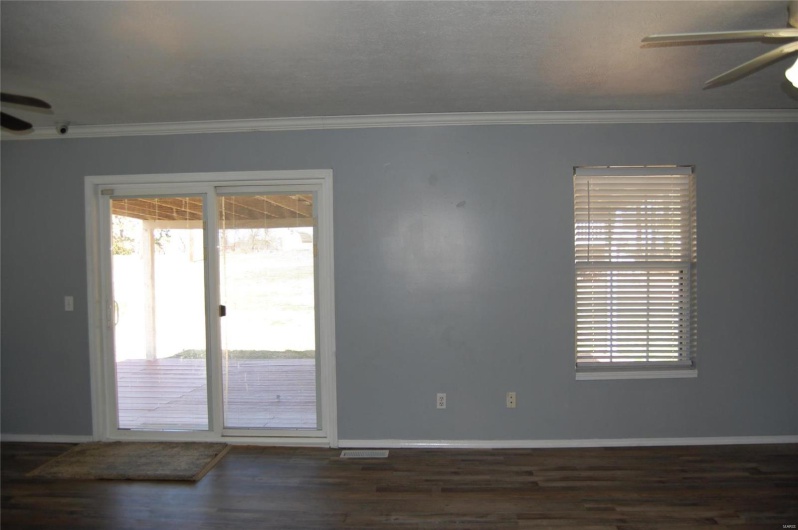 Unfurnished room featuring baseboards, wood finished floors, ceiling fan, and ornamental molding