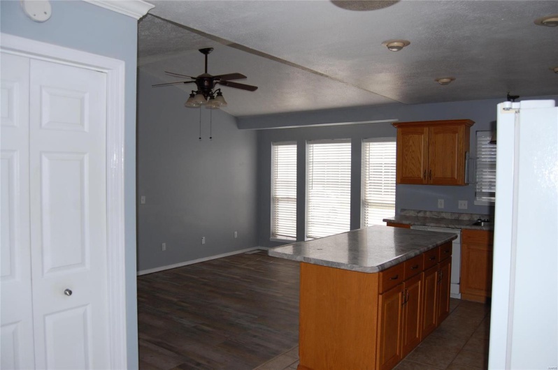 Kitchen featuring baseboards, ceiling fan, freestanding refrigerator, dishwashing machine, and brown cabinets