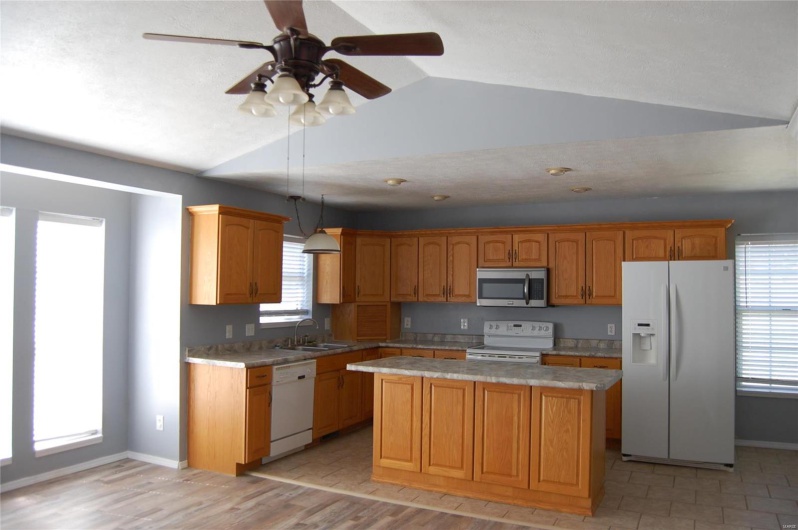 Kitchen featuring a wealth of natural light, a center island, light countertops, and white appliances