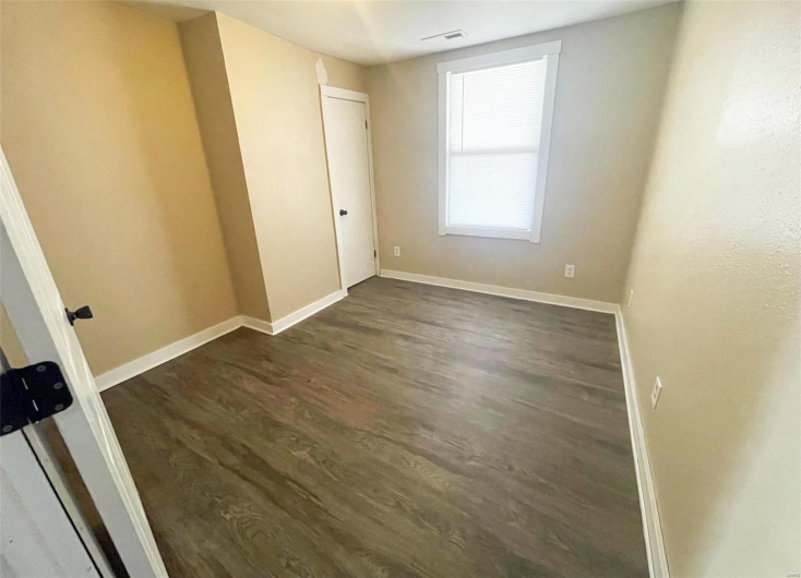 Empty room featuring visible vents, baseboards, and dark wood finished floors