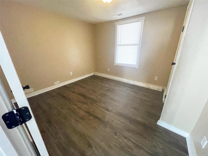 Empty room featuring baseboards, dark wood finished floors, and visible vents