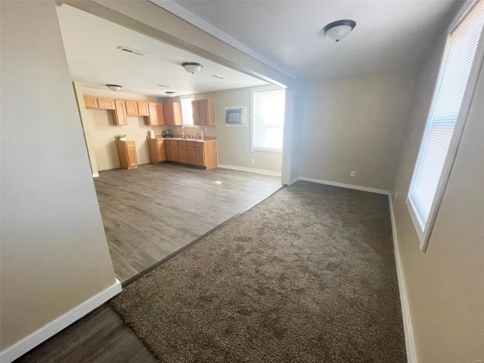 Unfurnished living room featuring wood finished floors, baseboards, visible vents, and a wealth of natural light